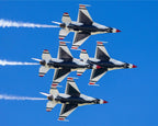 Four fighter jets performing a formation flight against a clear blue sky.