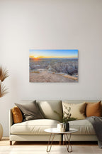 Fine art photography print of a South Dakota Badlands National Park sunrise casting golden light across rugged canyons and rock formations.