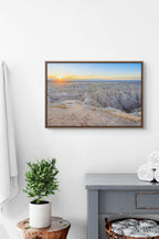 Fine art photography print of a South Dakota Badlands National Park sunrise casting golden light across rugged canyons and rock formations.