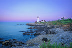Lighthouse on a rocky coastline with a purple sky